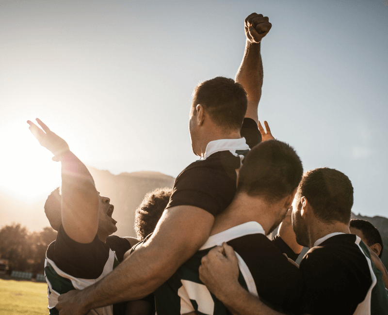 A close up of a sporting team cheering and holding up one of their team mates