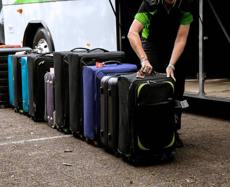 Suitcases lined up on the pavement as they are loaded onto a charter bus on the sunshine coast