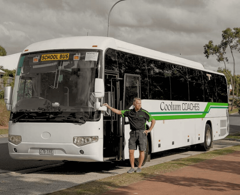 A coolum coaches bus driver stands in front of his school bus