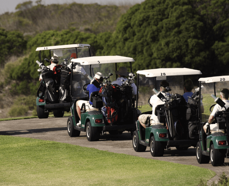 Golf carts being driven by men on a golf course on the sunshine coast