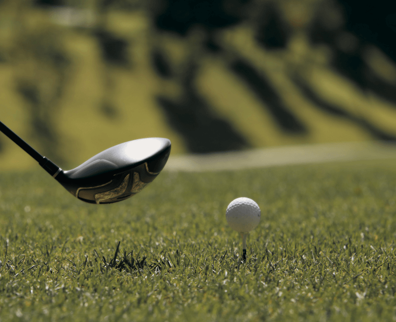 A close up of a golf club and a golf ball on the tee